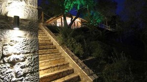Un escalier en pierre mène à une cabane en bois, et une source de lumière se trouve en haut.