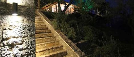Una escalera de piedra que conduce a una cabaña de madera con una luz en la parte superior.