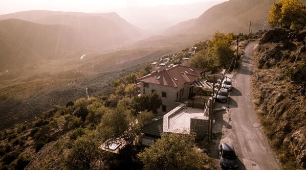 A building with a tiled roof, surrounded by trees and a mountainous landscape.