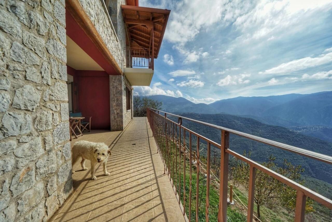 A stone building with a wooden deck and a balcony overlooking a mountainous landscape.