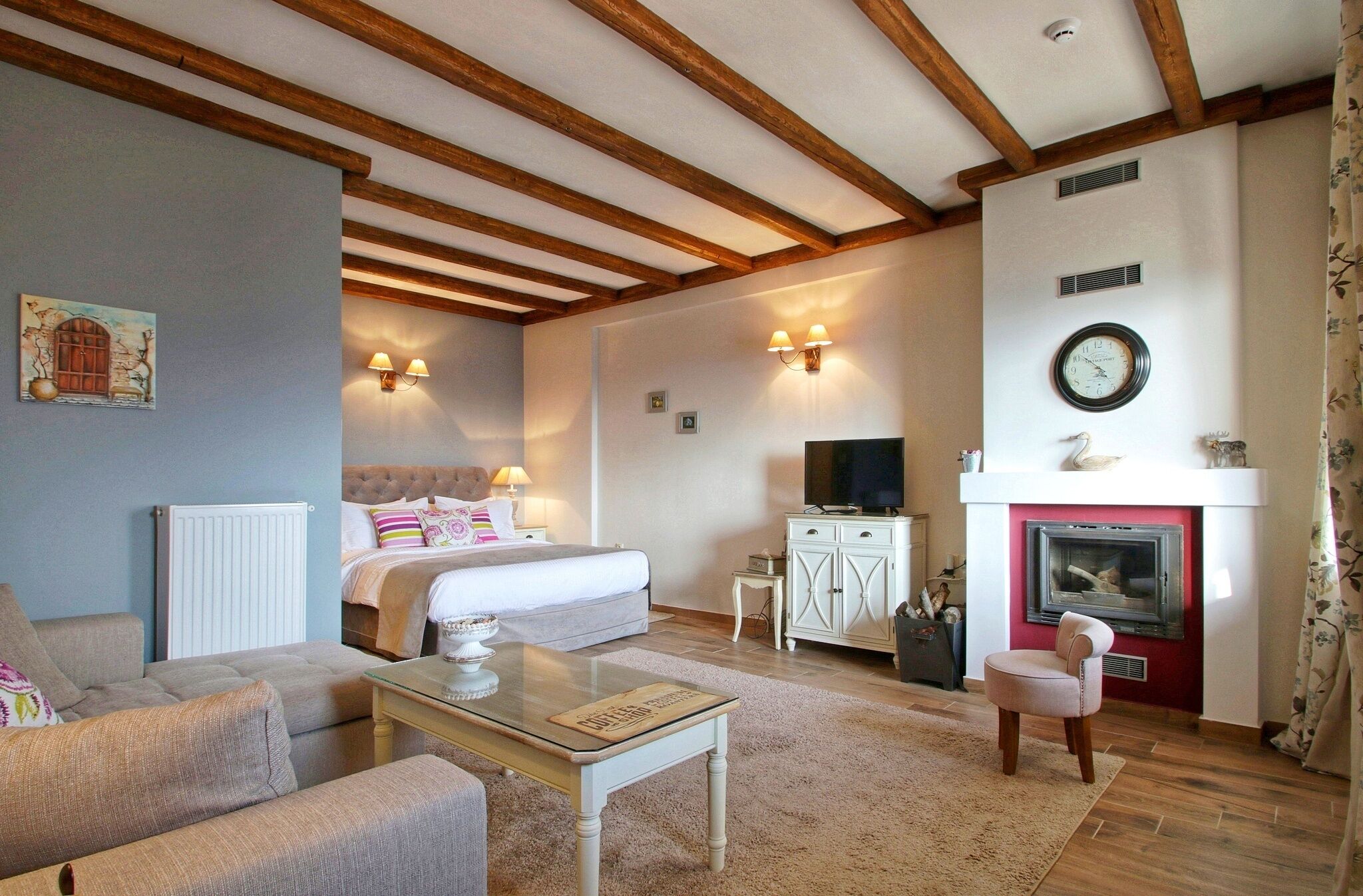 A cozy living room with a fireplace, a bed, and a television.