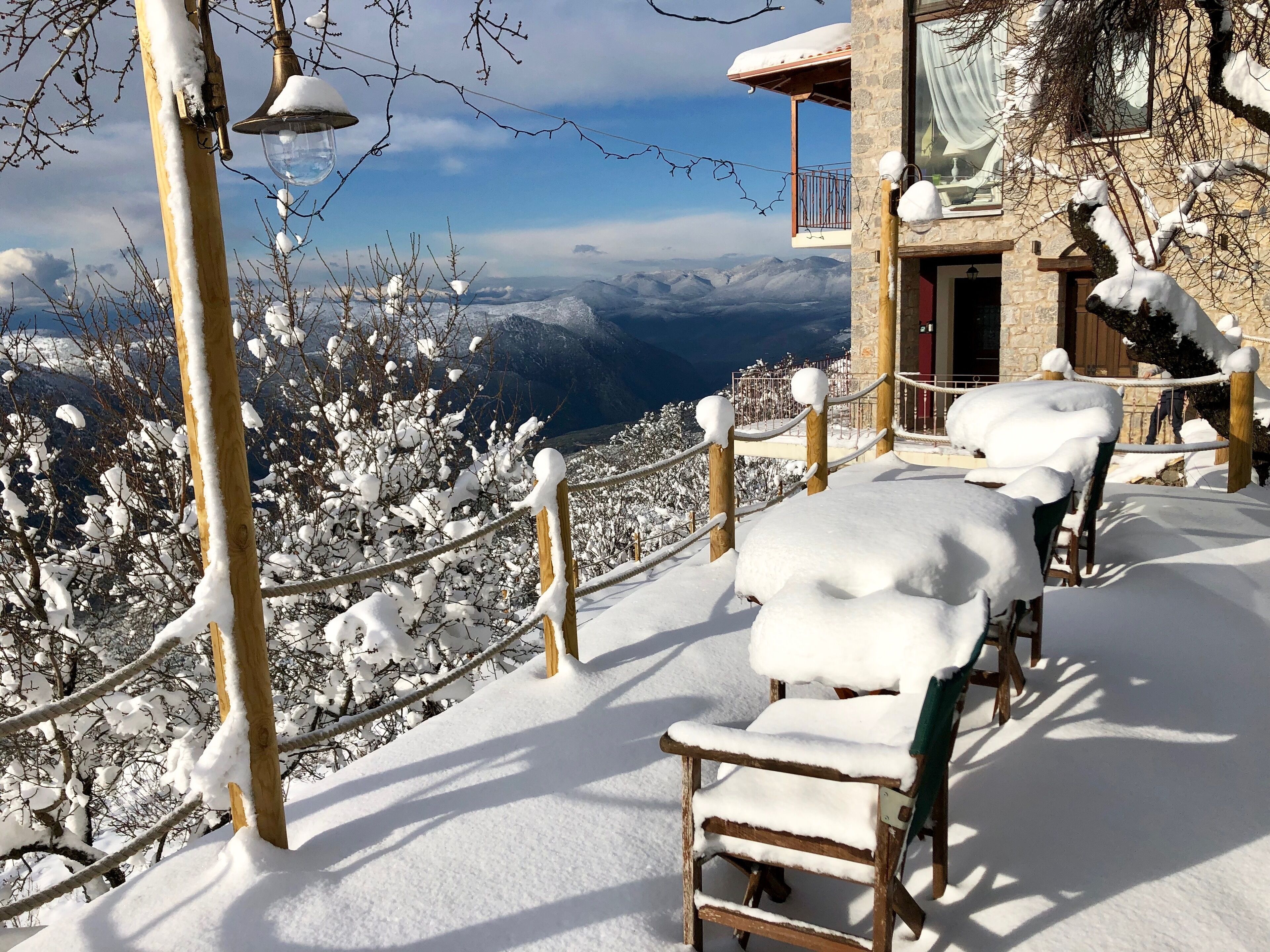 A snow-covered outdoor seating area with a view of mountains.