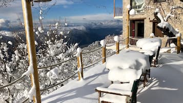 A snow-covered outdoor seating area with a view of mountains.