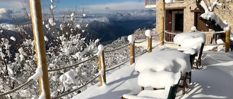 Un espacio de estar al aire libre cubierto de nieve con vistas a las montañas.