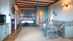 A cozy room with a bed, a sofa, a small table, and a television. - Almond House Suites Arachova - Adults Only (Distomo-Arachova-Antikyra)