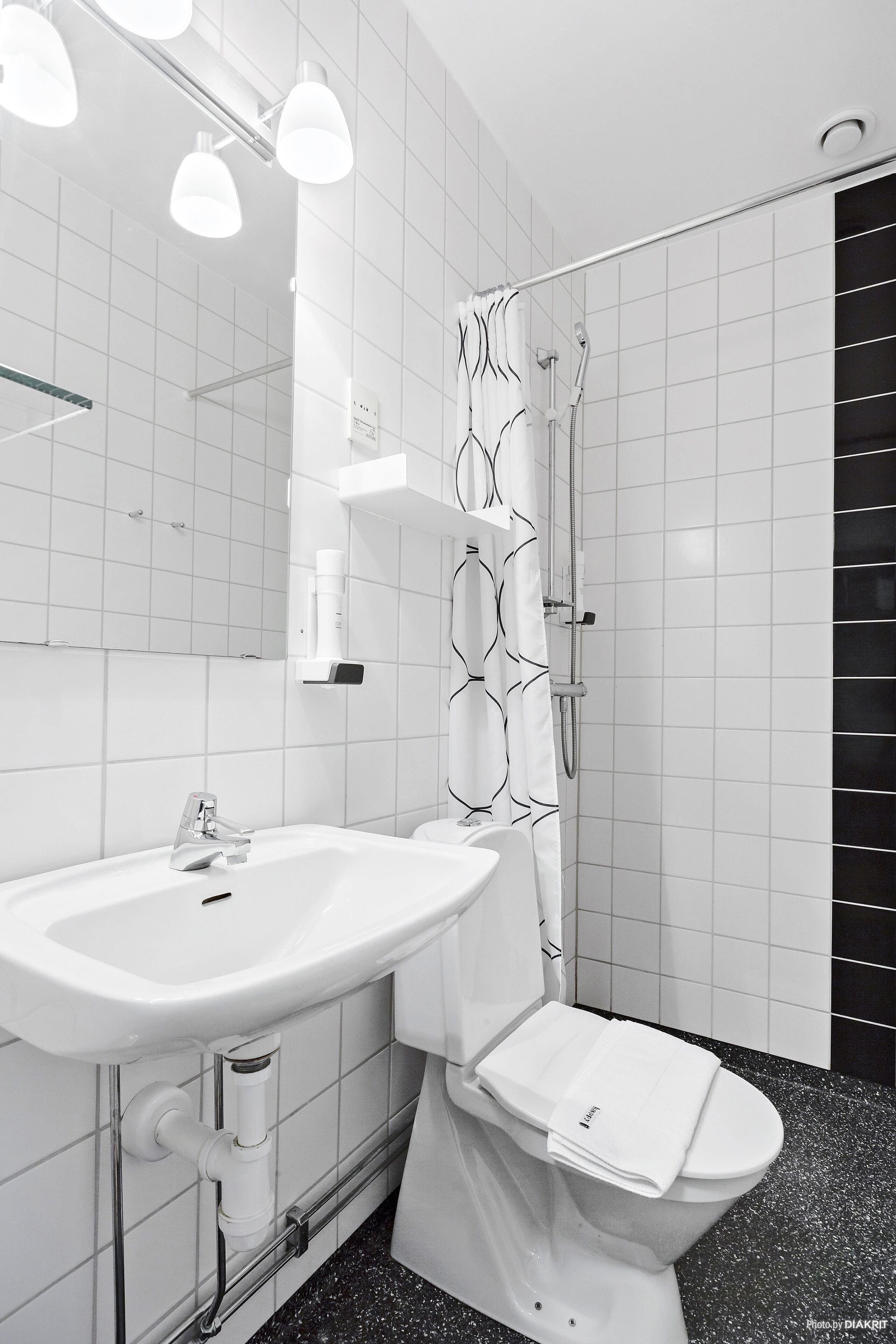 A modern bathroom with a white sink, toilet, and shower.