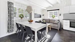 A modern kitchen with white cabinetry, a dining area with a white table and chairs, and a gray sofa. - First Camp Ånnaboda-Örebro (Garphyttan)