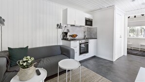 A modern kitchen with white cabinets, a built-in oven, and a microwave. - First Camp Ånnaboda-Örebro (Garphyttan)