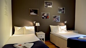 A hotel room with two beds, a nightstand with a lamp, and framed pictures on the wall. - First Camp Ånnaboda-Örebro (Garphyttan)