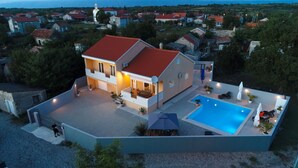 Une maison à deux étages avec une piscine, un espace salon extérieur et une vue sur le quartier environnant.