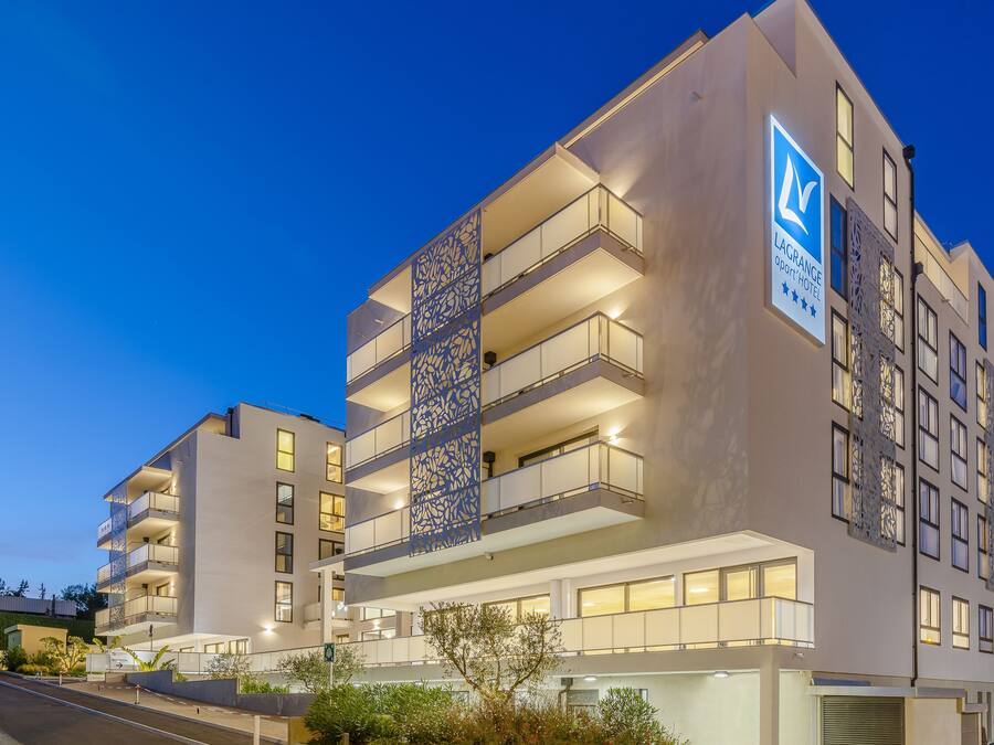 A multi-story hotel with balconies, a sign indicating it is a 4-star hotel, and a modern architectural design.
