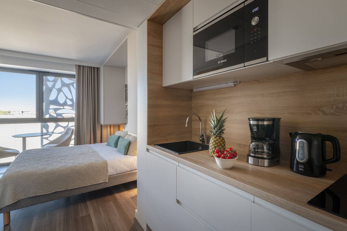 Ein modernes Hotelzimmer mit Küchenzeile, einem Bett mit Blick und einem Essbereich.