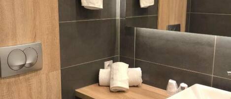 A modern bathroom with a wooden vanity, a white sink, and a toilet.