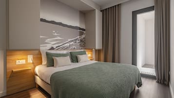 Een moderne hotelkamer met een groot bed, een nachtkastje, een wandlamp en uitzicht op het omliggende landschap door een raam.