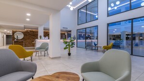 Een moderne lobby met een receptiebalie, zithoek en grote ramen.