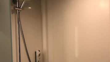 Une douche équipée d’un pommeau de douche à main et d’un panneau de commande fixé au mur.
