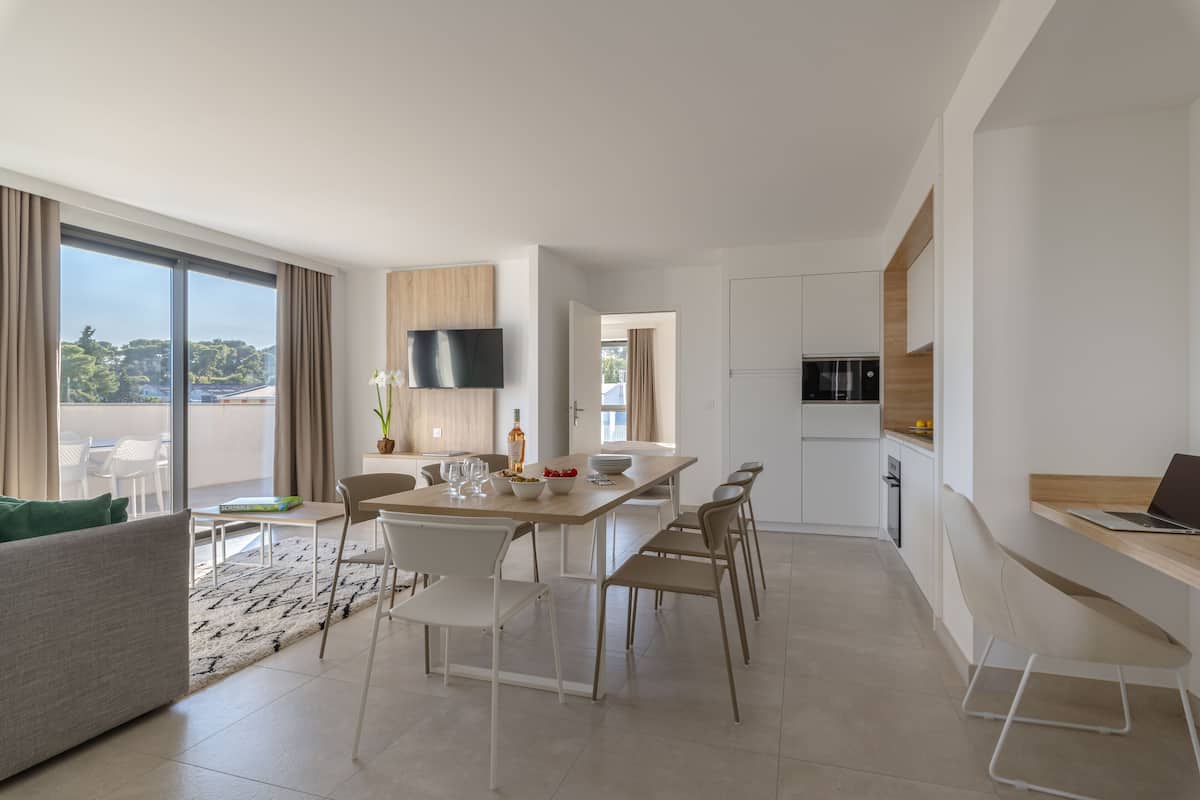 Ein modernes Wohnzimmer mit Essbereich, Küche und an der Wand befestigtem Fernseher.