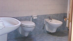 Een badkamer met dakraam, twee toiletten, een bidet en een wastafel.