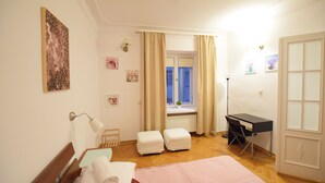 A bedroom with a bed, a desk, a chair, and a window with curtains. - Elegant Apartment Universitas (Warsaw)
