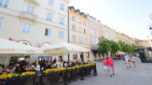 A street with outdoor seating at cafes, pedestrians, and historic buildings. - Elegant Apartment Universitas (Warsaw)