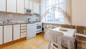 Une cuisine moderne avec des meubles blancs, un four à micro-ondes, une bouilloire et un coin repas comprenant une table et des chaises.