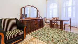 Une pièce comprenant un canapé, un meuble en bois, une table à manger avec des chaises et une grande fenêtre avec des rideaux.