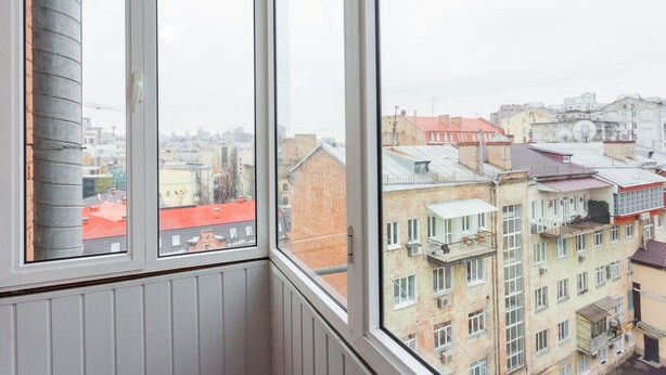 Une vue depuis une fenêtre donnant sur un paysage urbain avec de nombreux bâtiments, notamment des immeubles résidentiels et des bâtiments commerciaux.