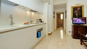 A modern kitchen with a built-in oven, a sink, and a television displaying a program.