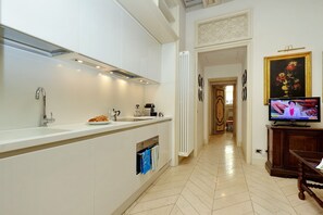 A modern kitchen with a built-in oven, a sink, and a television displaying a program.