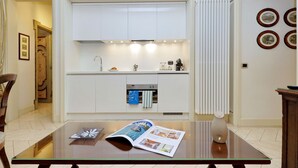A modern kitchen with white cabinets, a built-in oven, and a coffee machine.