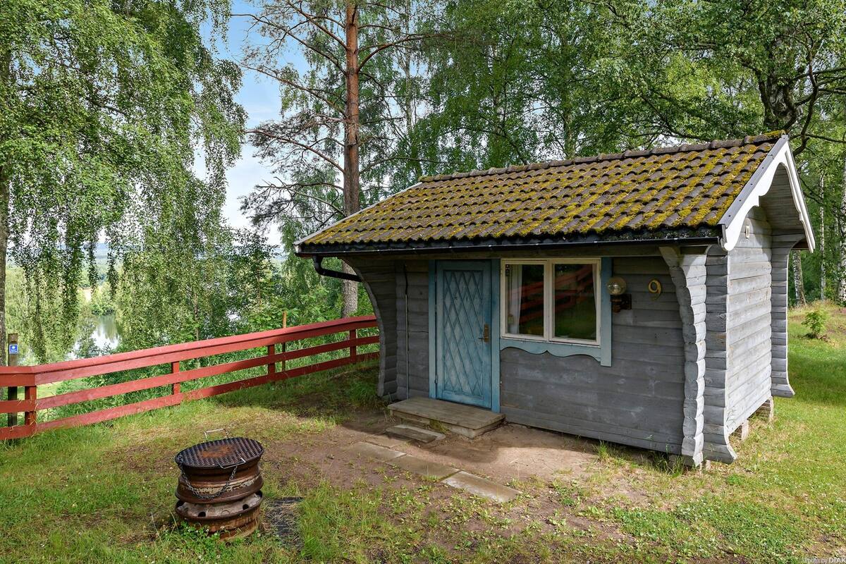 Une petite cabane en bois avec un toit recouvert de tuiles, une porte bleue et une fenêtre.