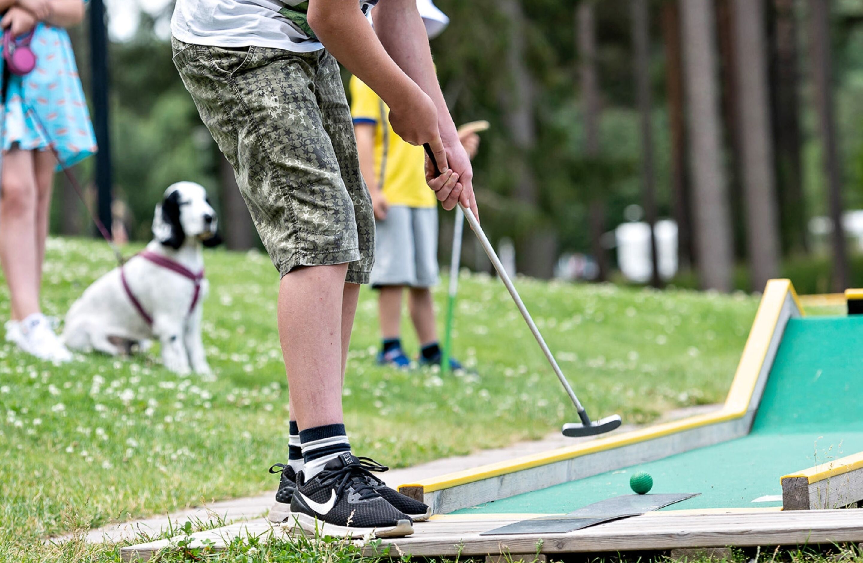 A person playing croquet on a grass field.