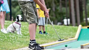 A person playing croquet on a grass field.