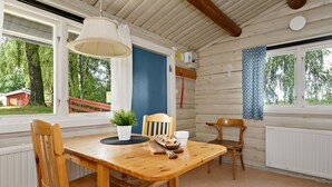 Une table à manger en bois, des chaises, un luminaire suspendu et une vue sur l’extérieur.