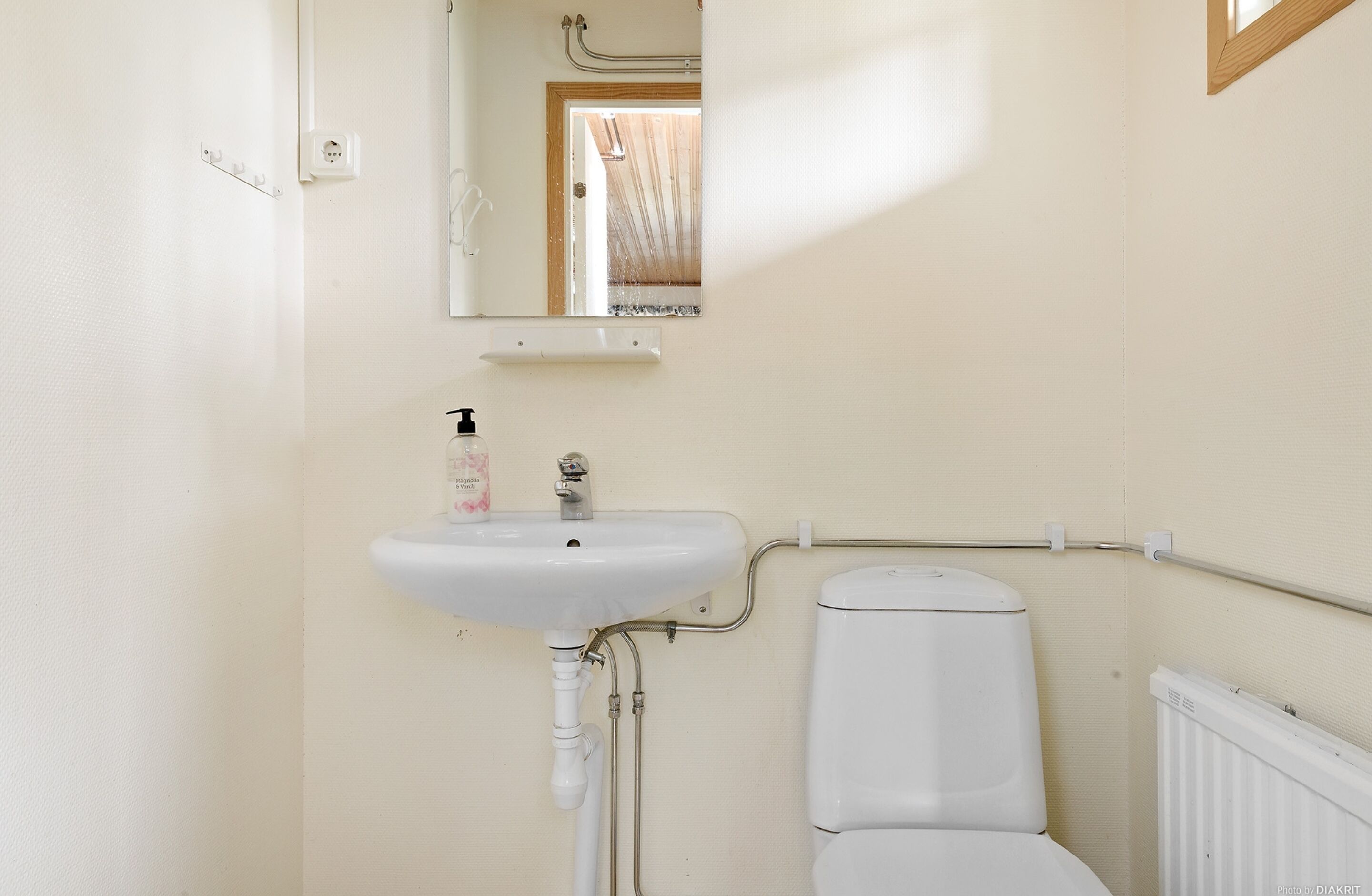 A bathroom with a white sink, mirror, and toilet.