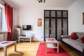 Una sala de estar con televisión, un sofá, una mesa de centro y un mueble.