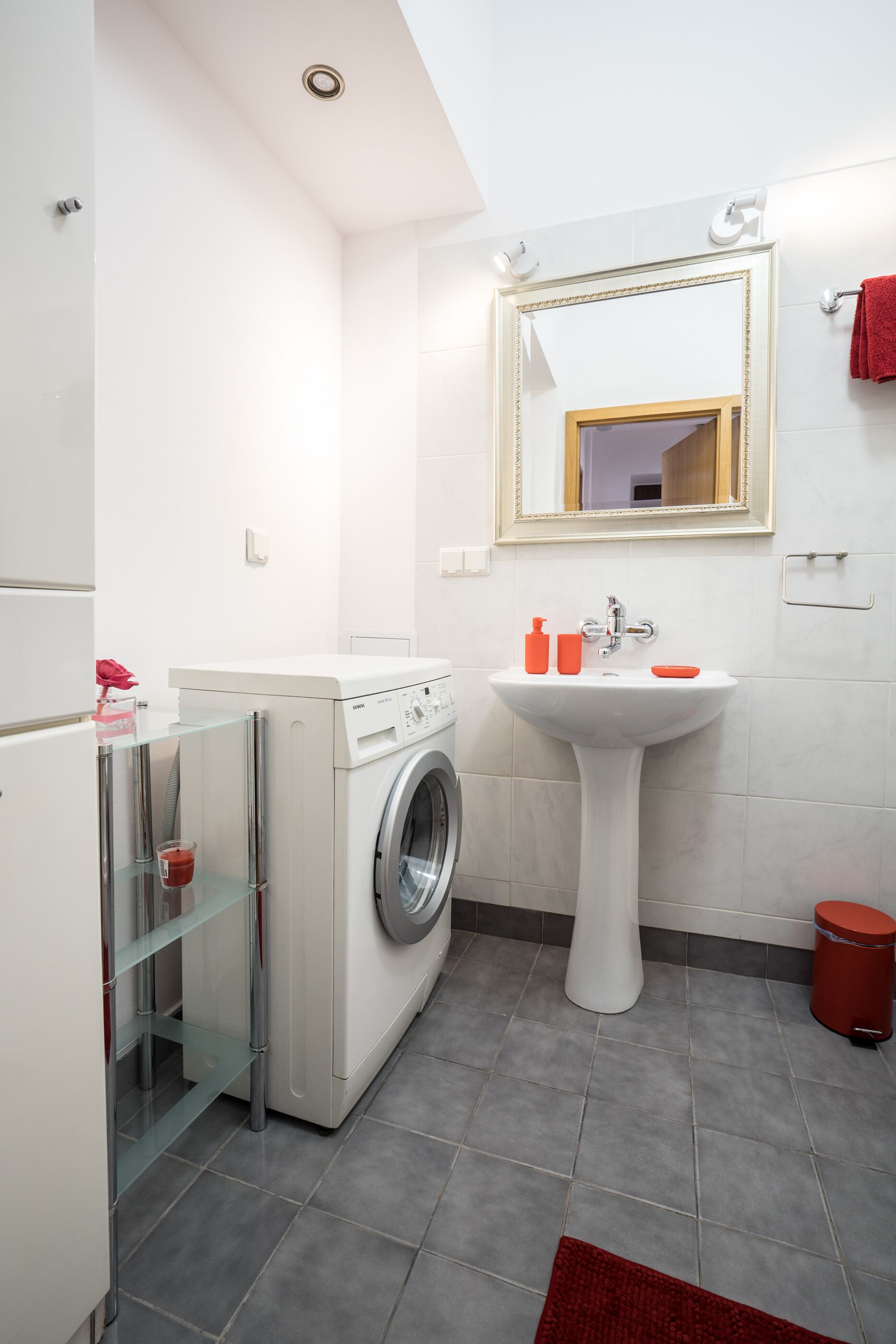 A modern bathroom with a washing machine, a sink, and a mirror.