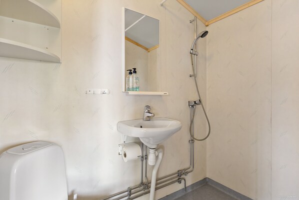 A bathroom with a white sink, a mirror, a shower, and a toilet.