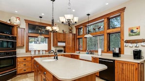A spacious kitchen with wooden cabinets, a large island, and a view of the outdoors. - Smiths Ferry Cabin by Cabarton & Snowmobile Trails (Smiths Ferry)