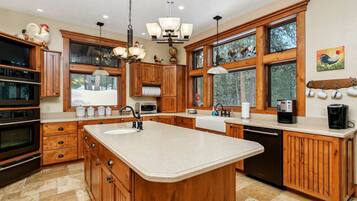 Une cuisine spacieuse avec des meubles en bois, un grand îlot central et une vue sur l’extérieur.
