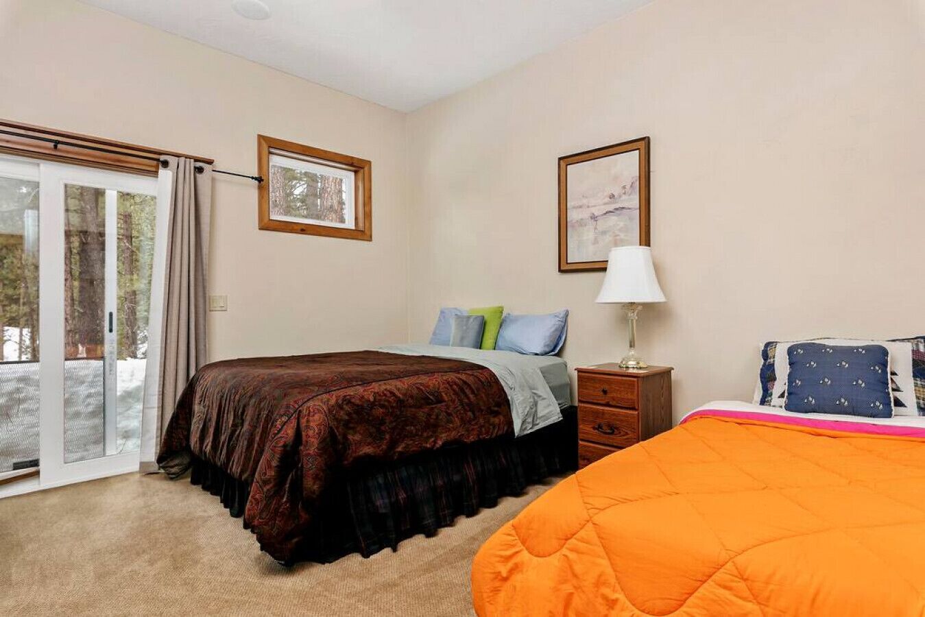 A bedroom with a bed, a nightstand, a window, and a door.