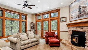 A spacious living room with large windows, a fireplace, a ceiling fan, and a painting on the wall. - Smiths Ferry Cabin by Cabarton & Snowmobile Trails (Smiths Ferry)