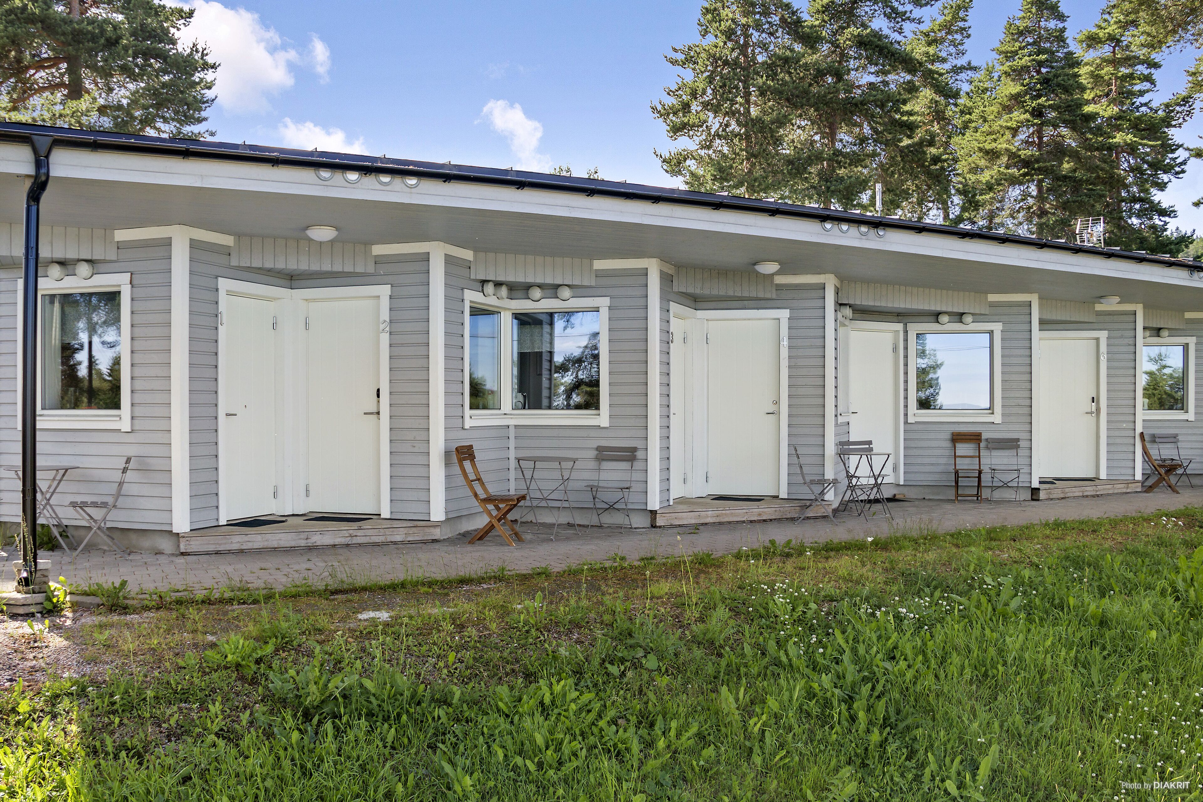 Ett enplanshus på hjul med en inglasad veranda, flera dörrar och fönster.
