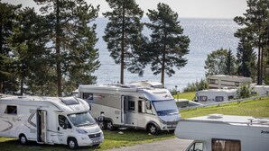 En række campingvogne parkeret på en græsplæne med udsigt til havet.