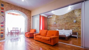 Une chambre moderne avec un mur en briques, un plancher en bois, un canapé, un lit et un coin repas.