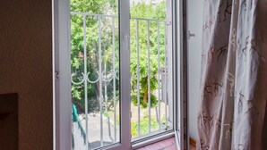 Une pièce dotée d’une porte-fenêtre coulissante donnant sur un balcon agrémenté d’une rambarde en métal et de plantes.