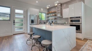 Una cocina moderna con una isla grande, electrodomésticos de acero inoxidable y vistas al exterior.