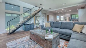 Un salón amplio con una escalera moderna, un sofá gris y una mesa de centro de madera.
