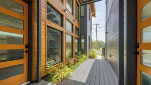 Un edificio moderno con amplios ventanales, revestimiento de madera y un estrecho sendero con plantas.