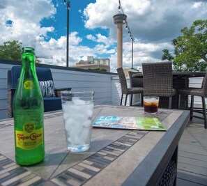 Eine Dachterrasse mit Blick auf einen Turm, eine Flasche Toster Chica, ein Glas Wasser und eine Speisekarte.